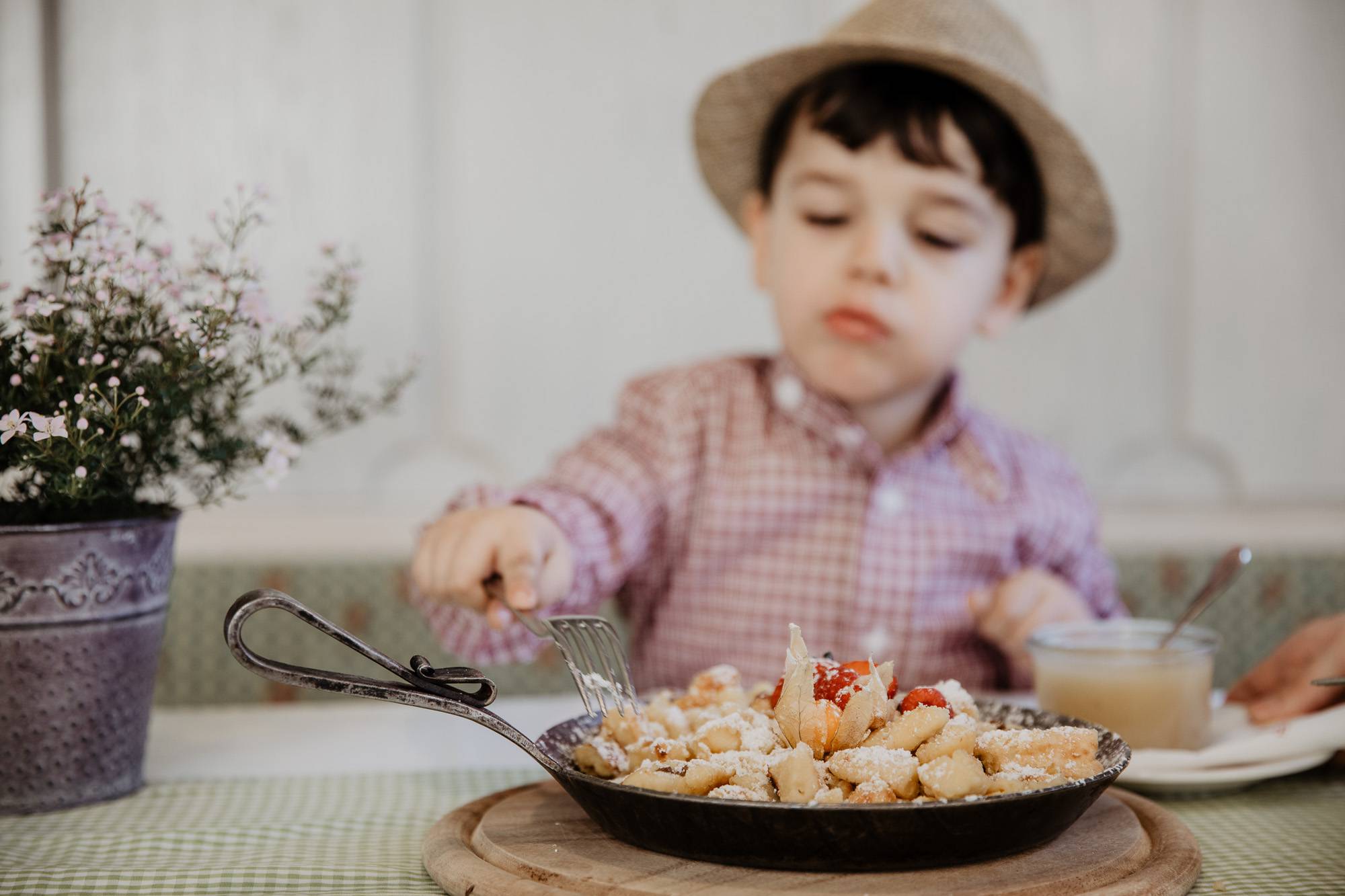 Kind mit Hund probiert frischen Kaiserschmarrn in Gusspfanne