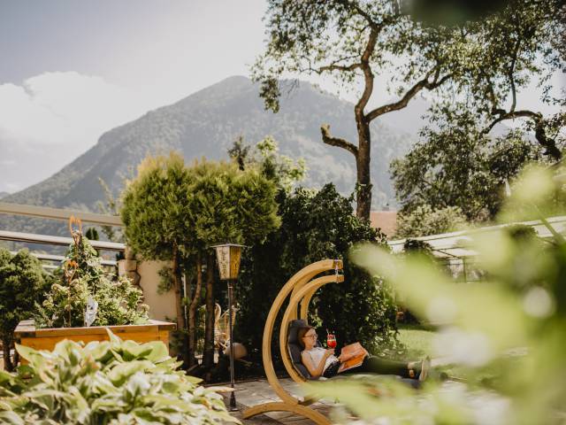 Blick in den Hotelgarten mit Gartenliege und Ausblick auf die Berge im Chiemgau