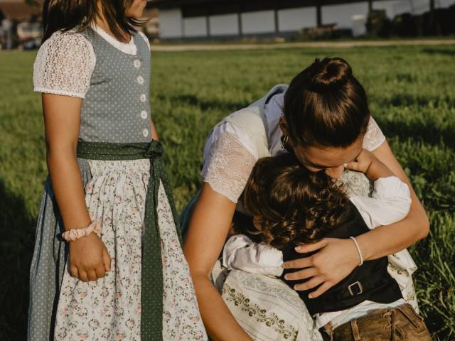 Frau umarmt Kind auf der Feldwiese