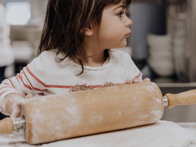 Kleinkind hilft mit dem Nudelholz beim backen