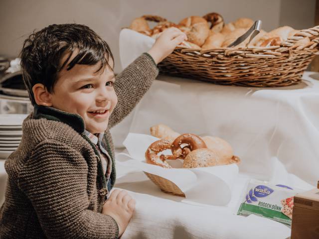 kleiner Junge bedient sich am Brotkorb des Frühstücksbuffet im Weßnerhof