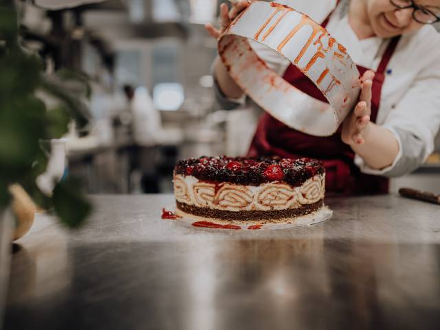Konditormeister beim Anrichten einer Torte