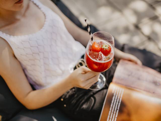 Frau liegt in Liegestuhl und hält eine Sommerschorle in der Hand