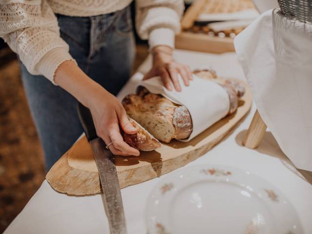 Person schneidet frisches Brot auf einem Holzbrett