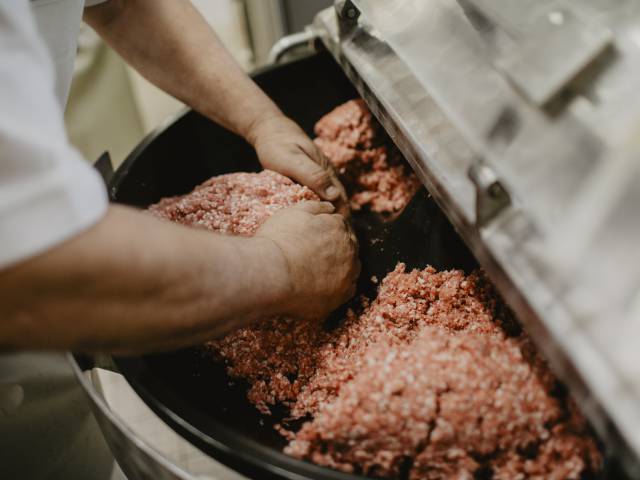 Frisches Hackfleisch wird weiterverarbeitet zur Wurst in einer Maschine