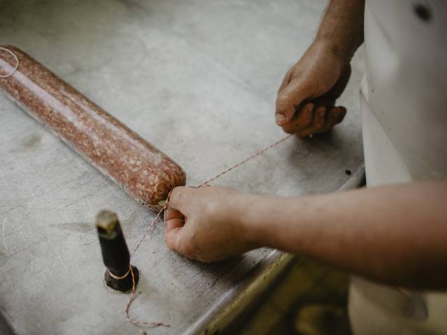 Metzger schnürt die hausgemachte Salami in der Hofmetzgerei Weßnerhof