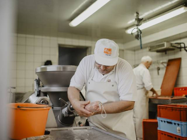 Mitarbeiter der Hofmetzgerei beim herstellen einer Wurst