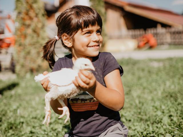 Mädchen hält Huhn in den Händen uns wirkt ziemlich stolz dabei