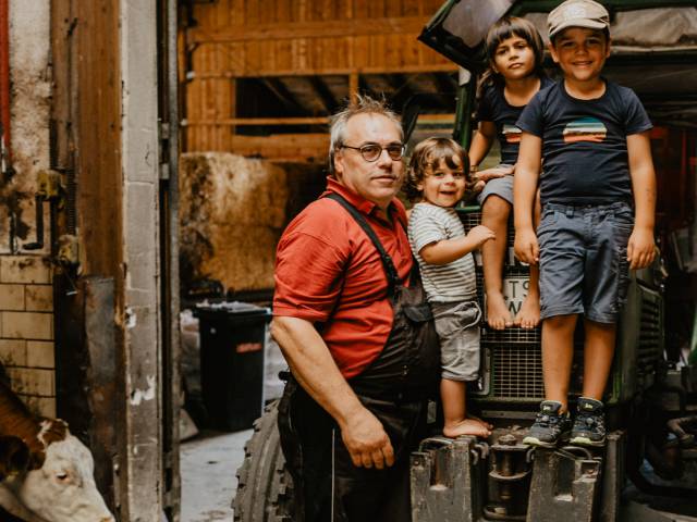 Kinder mit Opa posen vor Traktor im Stall