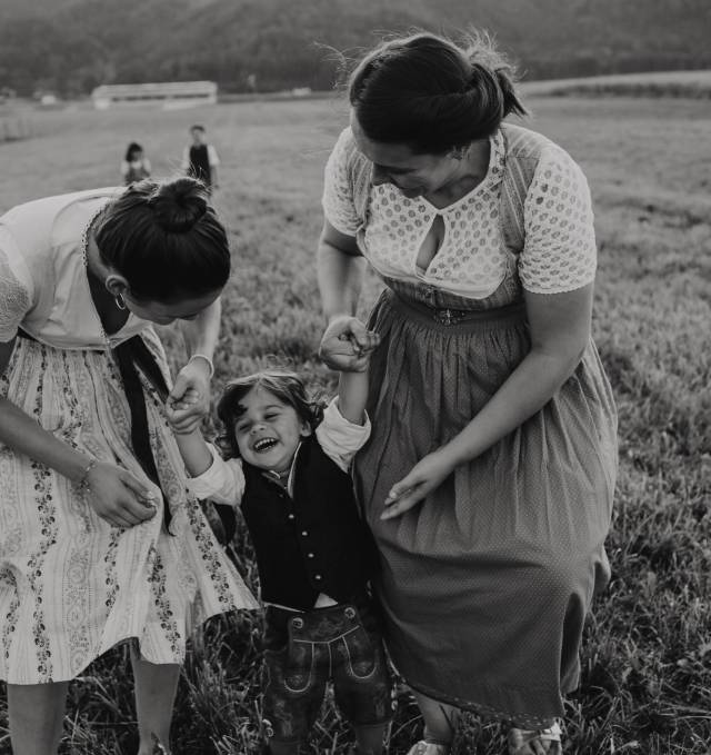Frauen halten mit Kind in der Mitte Händchen auf einem Feld