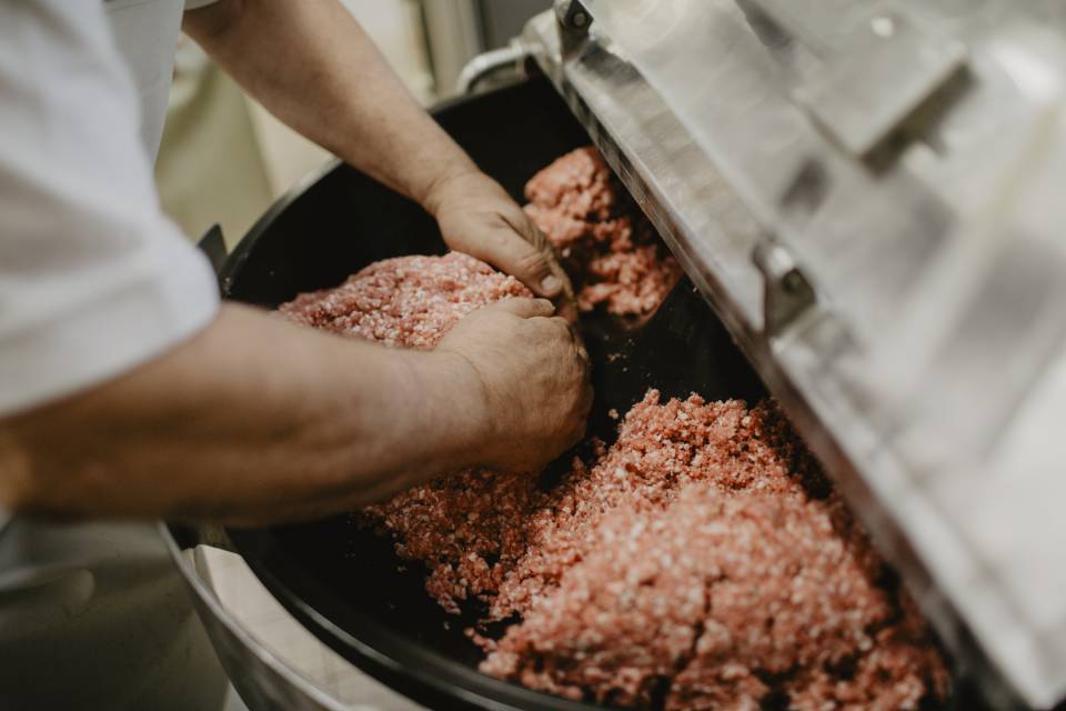 Frisches Hackfleisch wird weiterverarbeitet zur Wurst in einer Maschine 