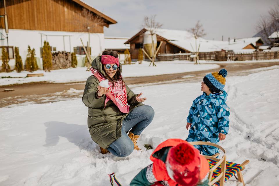 Mutter und Kinder spielen im Schnee