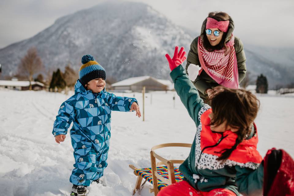 Kinder mit Mutter spielen im Schnee mit Schlitten